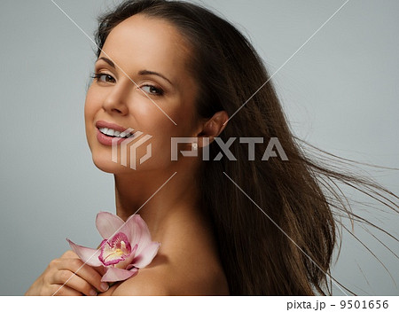 Young beautiful brunette woman with waving hair and orchid flower Young beautiful brunette woman with waving hair and orchid flower 9501656