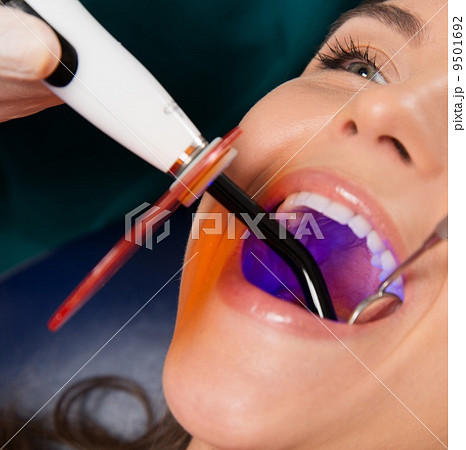 Young woman patient stopping treatment with dental UV light equipment 9501692