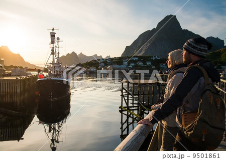 Young travellers couple looking at sunset in Reine village, Norway Young travellers couple looking at sunset in Reine village, Norway 9501861