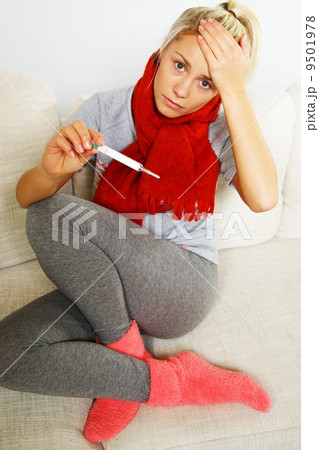 Sick young woman with thermometer at home 9501978