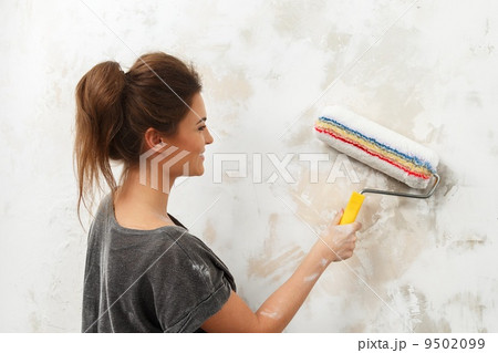 Happy beautiful young woman doing wall painting 9502099