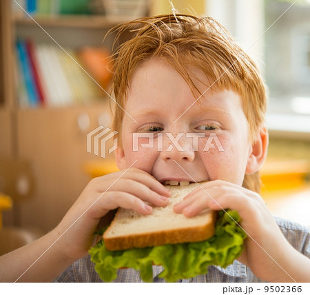 Little redhead schoolboy eating sandwich in class Little redhead schoolboy eating sandwich in class 9502366