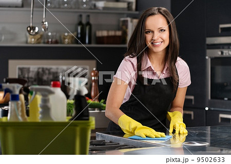 Beautiful cheerful brunette woman in gloves cleaning modern kitchen Beautiful cheerful brunette woman in gloves cleaning modern kitchen 9502633