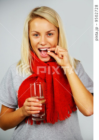 Sick young blond woman with pills and glass of water 9502728