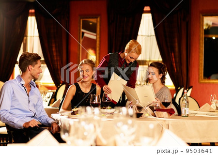 Group of young friends with menus choosing in a luxury restaurant 9503641