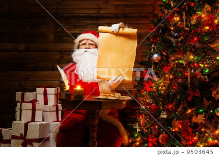 Santa Claus in wooden home interior holding blank wish list scroll 9503645