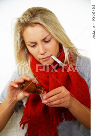 Sick young blond woman with thermometer bottle of mixture 9503763