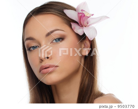 Young brunette girl with beautiful smile and orchid flower in her hair Young brunette girl with beautiful smile and orchid flower in her hair 9503770