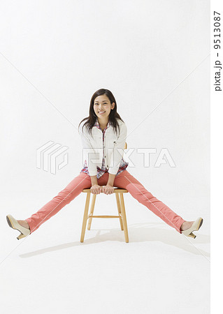 足を広げて椅子に座る女性の写真素材