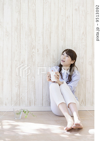 壁にもたれて座る女性の写真素材
