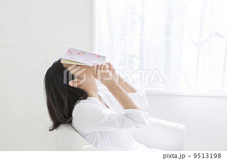 本で顔を覆う女性の写真素材