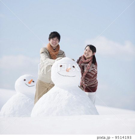 雪だるまを作るカップルの写真素材