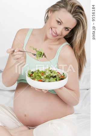 .Pregnant woman in bed eating salad .Pregnant woman in bed eating salad 9556184