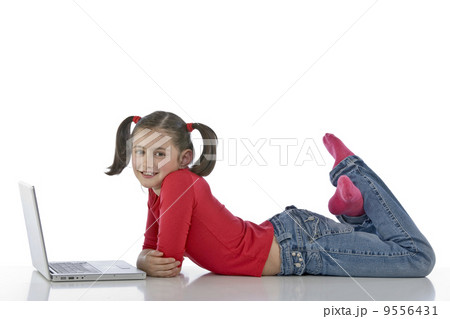 Adorable caucasian little girl lying with laptop 9556431