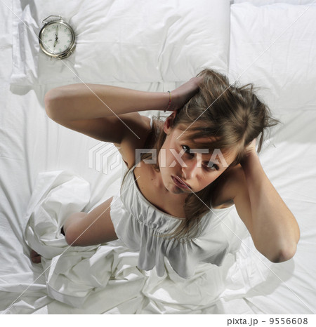 Woman in bed with alarm clock 9556608