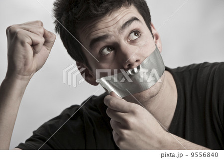 Man with mouth covered by masking tape preventing speech.. 9556840