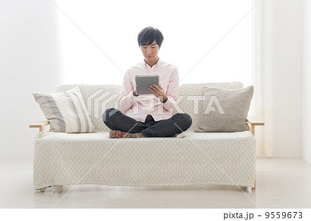 男性 リラックス タブレット あぐら 座る 正面の写真素材