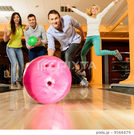 Group of four young smiling people playing bowling 9566879