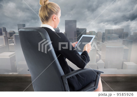 Composite image of businesswoman sitting on swivel chair with ta 9585926