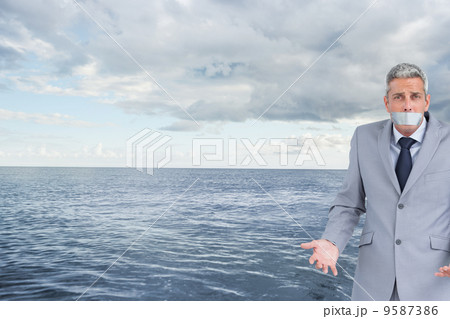 Composite image of businessman gagged with adhesive tape on mout Composite image of businessman gagged with adhesive tape on mout 9587386