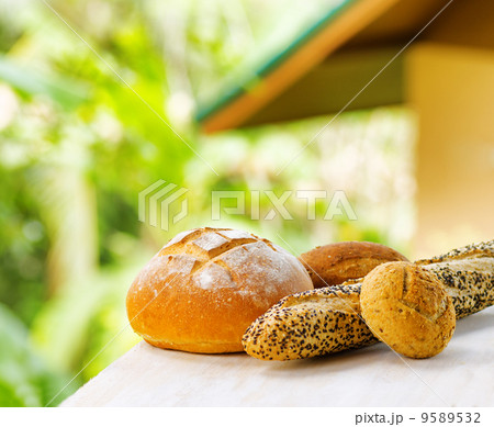 Fresh bread on white wooden table on rural landscape background 9589532