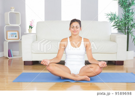 Front view of fit brunette woman relaxing in lotus position on a Front view of fit brunette woman relaxing in lotus position on a 9589698