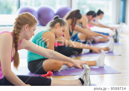 Fitness class and instructor stretching legs 9589714