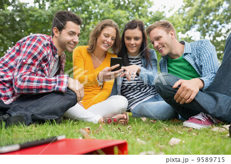 Happy college students looking at mobile phone in park 9589715