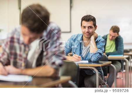 Male student with others writing notes in classroom Male student with others writing notes in classroom 9589726