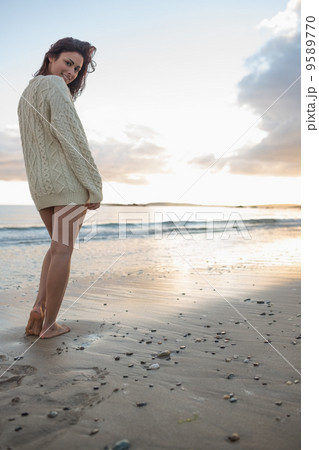Full length of a woman in sweater standing on beach 9589770