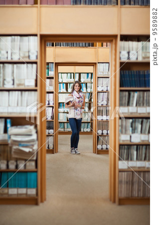 Full lenght of a female student standing in the library Full lenght of a female student standing in the library 9589882