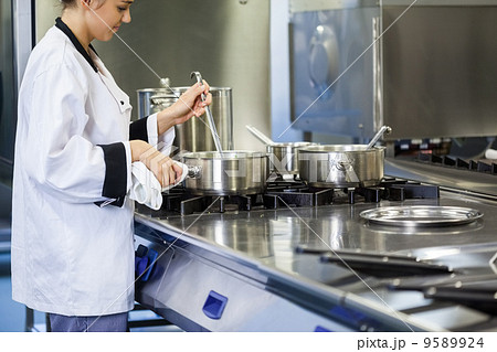 Young chef stirring with ladle 9589924