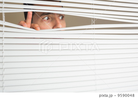Scared male eyes spying through roller blind 9590048