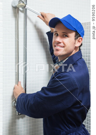 Smiling plumber repairing shower head Smiling plumber repairing shower head 9590206
