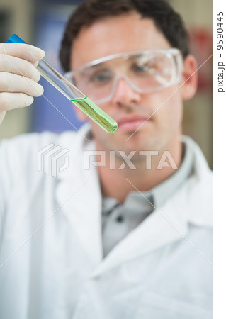 Scientist analyzing green solution in test tube at the lab 9590445