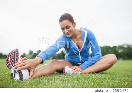 Woman stretching her leg while sitting on the grass Woman stretching her leg while sitting on the grass 9590474