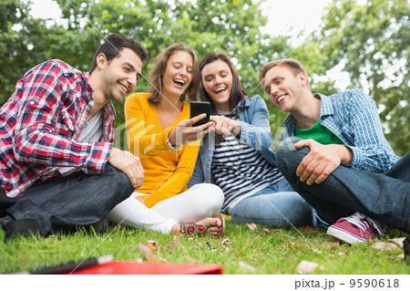 Happy college students looking at mobile phone in park 9590618