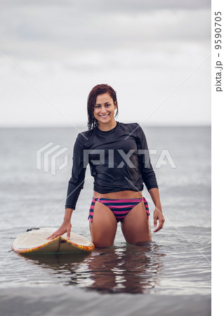 Portrait of a smiling woman with surfboard in water Portrait of a smiling woman with surfboard in water 9590705