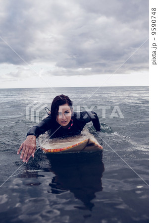 Woman swimming over surfboard in water Woman swimming over surfboard in water 9590748