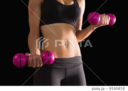 Slender active woman lifting pink dumbbells Slender active woman lifting pink dumbbells 9590858