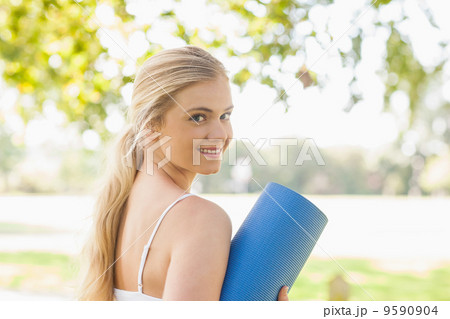 Beautiful sporty woman posing holding an exercise mat Beautiful sporty woman posing holding an exercise mat 9590904