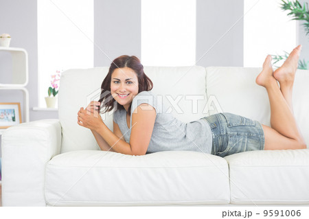 Portrait of pretty brunette woman lying on her couch in the livi Portrait of pretty brunette woman lying on her couch in the livi 9591006