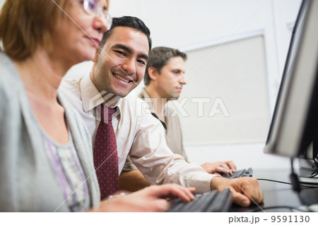 Teacher and mature students in computer room 9591130