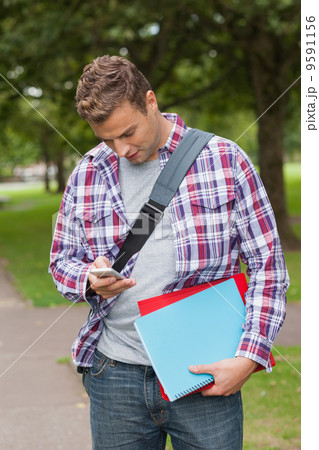 Handsome casual student standing and texting Handsome casual student standing and texting 9591156