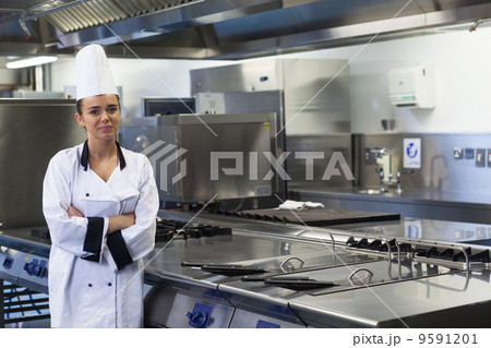 Young happy chef standing next to work surface arms crossed Young happy chef standing next to work surface arms crossed 9591201