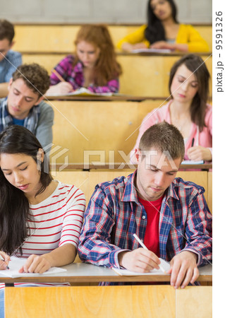 Students sitting at the lecture hall while writing Students sitting at the lecture hall while writing 9591326