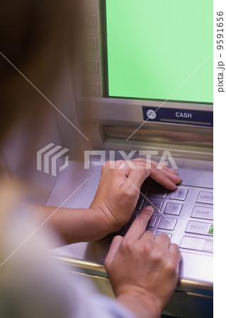Woman entering pin and covering keyboard Woman entering pin and covering keyboard 9591656