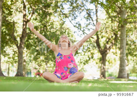 Cheerful blonde woman relaxing on a lawn 9591667