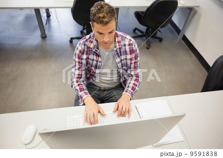 Handsome stern student working on computer 9591838
