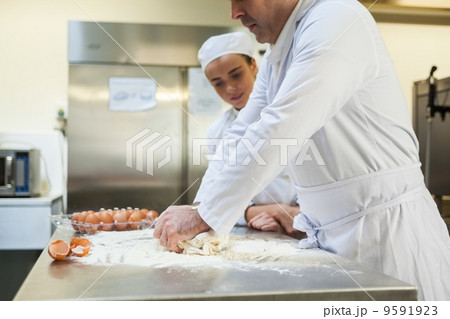 Serious head chef kneading dough 9591923